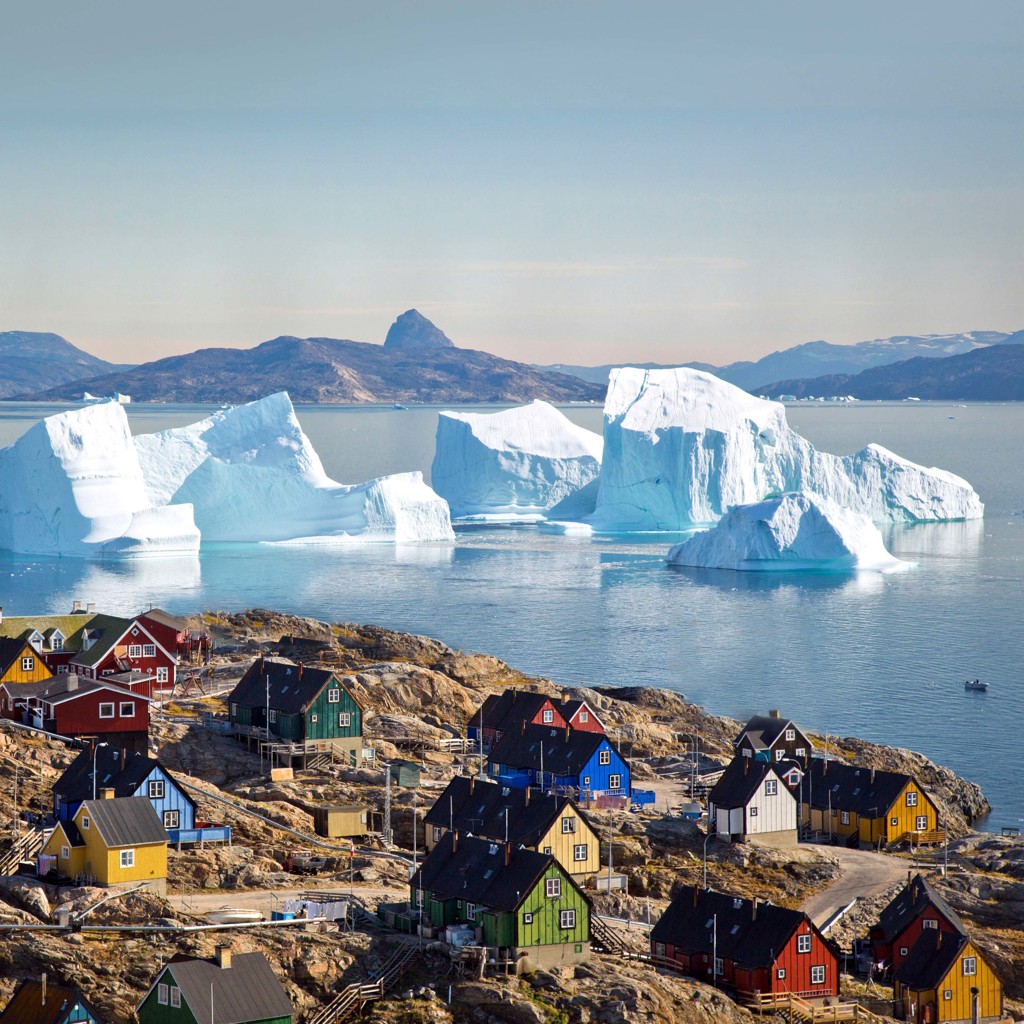 Gekleurde huizen in Ilulissat met drijvende ijsbergen in Disko Bay, Groenland.