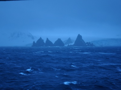 Ruige rotsformaties in de mist langs de kust van Antarctica tijdens de rondreisroute.