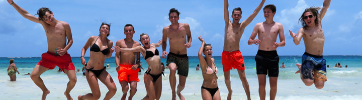Springende familie op het strand in Mexico tijdens een familiereis.