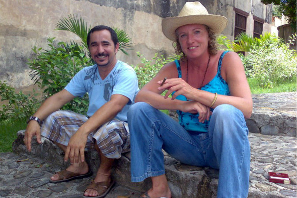 Reizigers bij een casas particulares in Cuba, zittend op stenen treden in een groene binnenplaats.