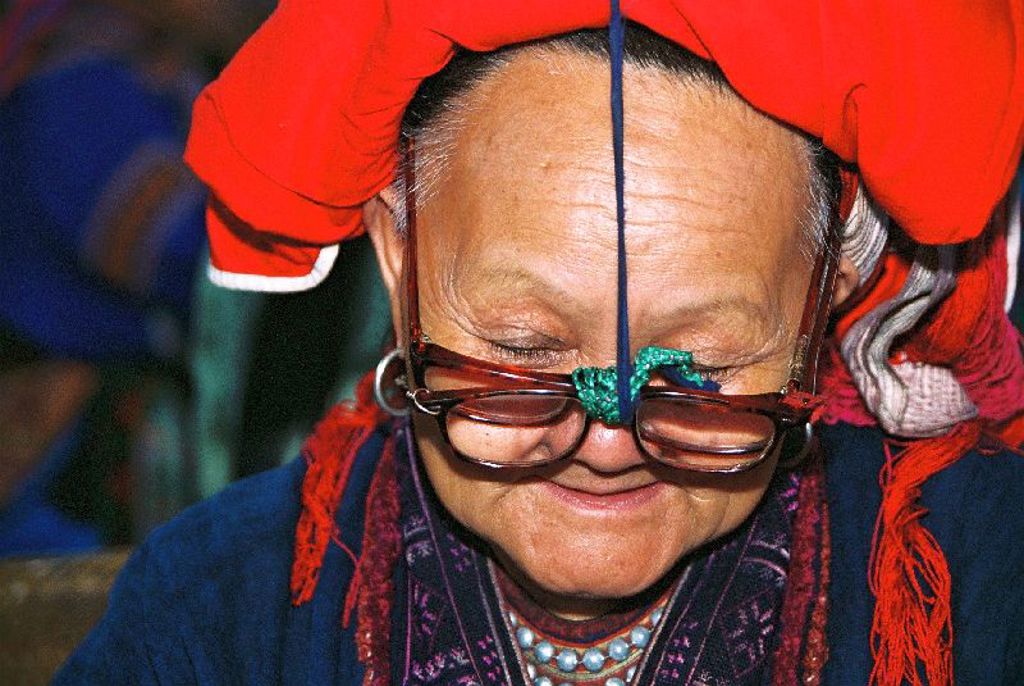 Portret van vrouw in traditionele kleding met rode hoofddoek en bril tijdens groepsrondreis Vietnam.