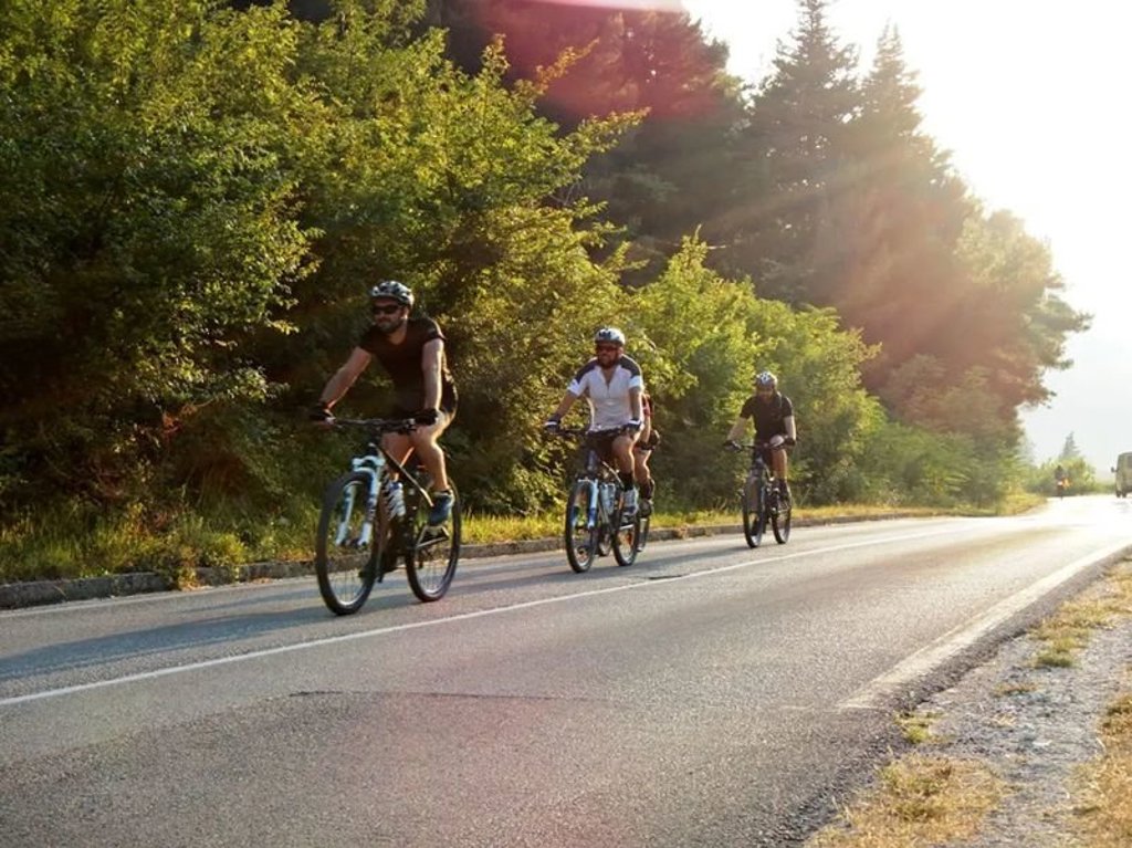 Groep fietsers tijdens fietsvakantie op de Balkan, met uitzicht op een historische stad.