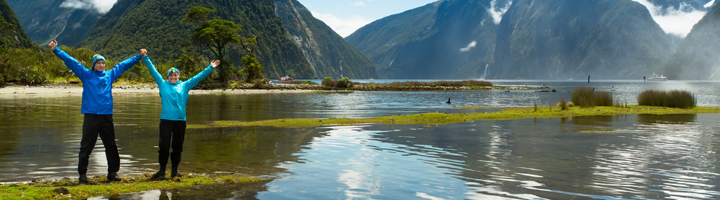 Reizigers bij Milford Sound met reflectie in het water en bergen op de achtergrond, Nieuw-Zeeland.