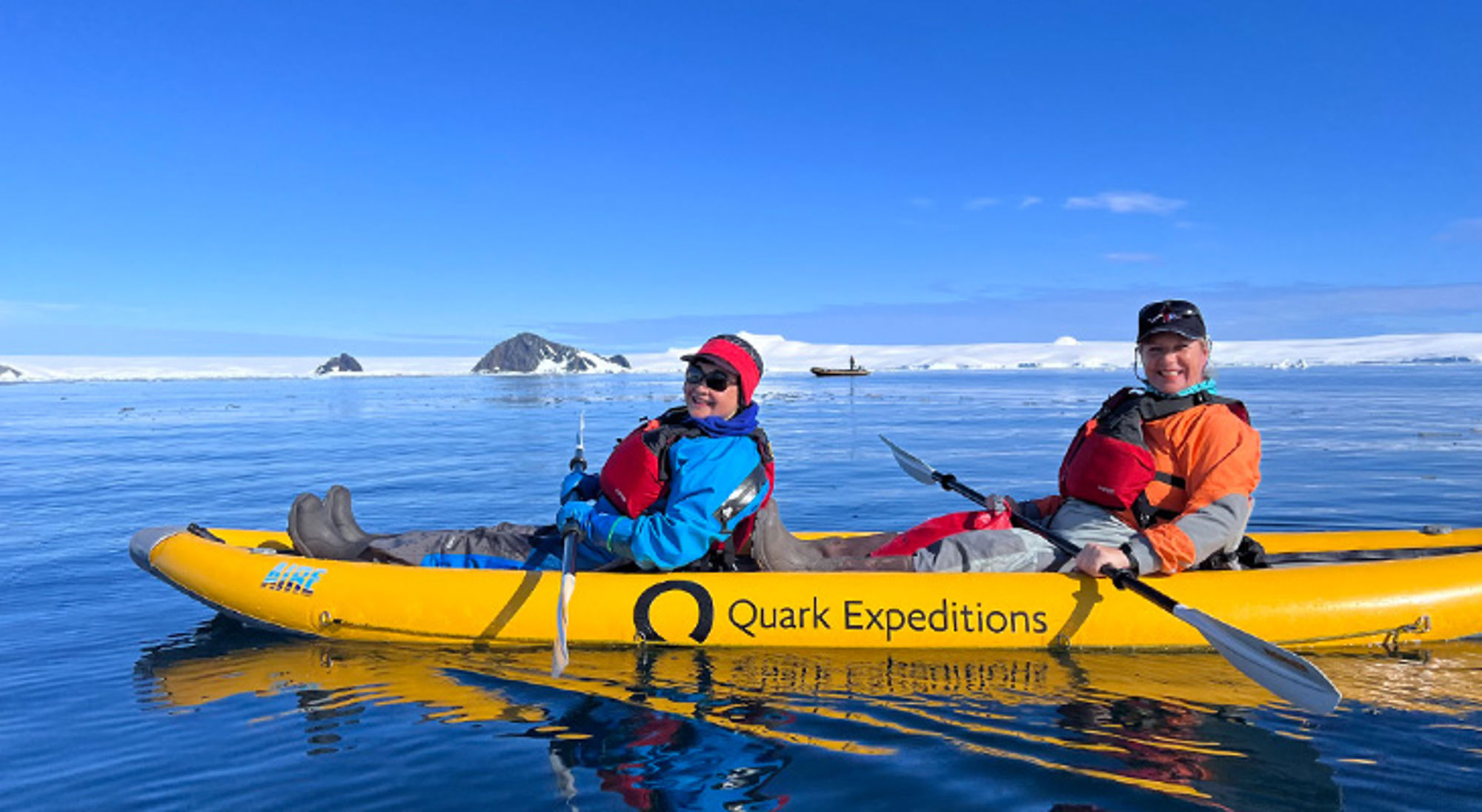 Peddelen Antarctica Twee reizigers kajakken op zee bij Antarctica, met ijs en bergen op de achtergrond.