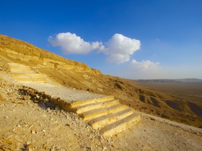 Uitzicht over de Egyptische woestijn met stenen traptreden langs een rotswand onder een blauwe lucht.