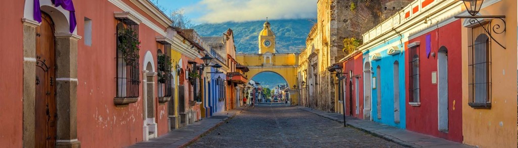 Kleurrijke straat in Antigua Guatemala met de Arco de Santa Catalina en vulkaan op de achtergrond.