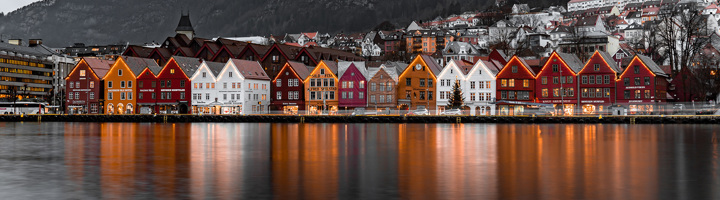 Kleurrijke houten huizen aan de Bryggen-kade in Bergen, Noorwegen, met reflectie in het water.