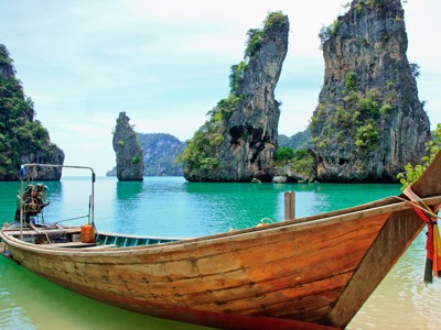 Longtailboot in turkooizen zee bij kalkstenen rotsen in Zuid-Thailand.