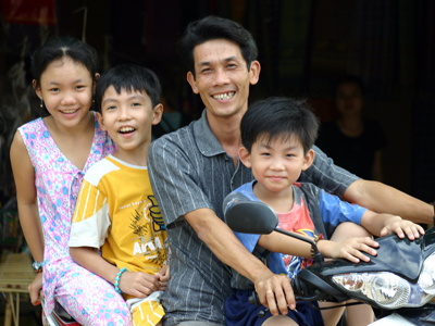 Vietnamees gezin op een scooter, glimlachend in de straat tijdens Route Vietnam.