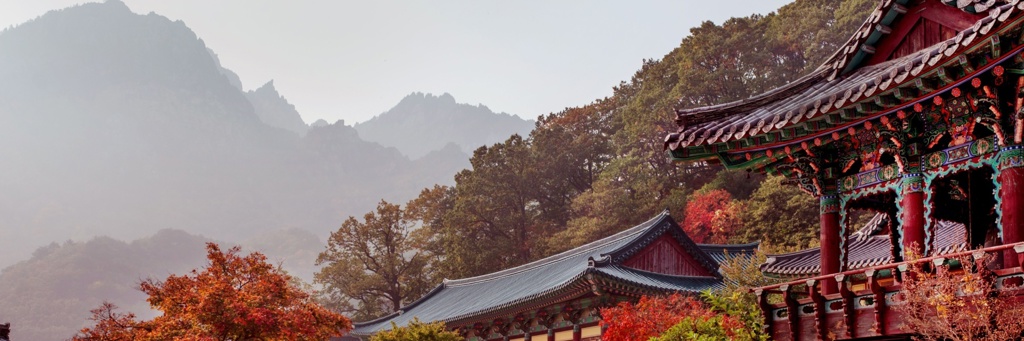 Koreaanse tempel met kleurrijk dak in herfstkleuren, met mistige bergen op de achtergrond in Zuid-Korea.