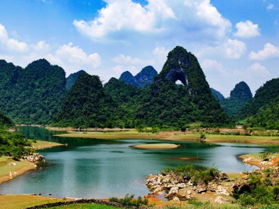 Karstbergen met grotopening bij een rivierlandschap in Vietnam tijdens de Route Vietnam.