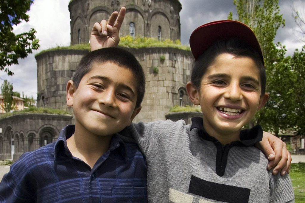 Twee lachende jongens poseren voor een historische stenen toren tijdens de rondreis Turkije hoogtepunten.