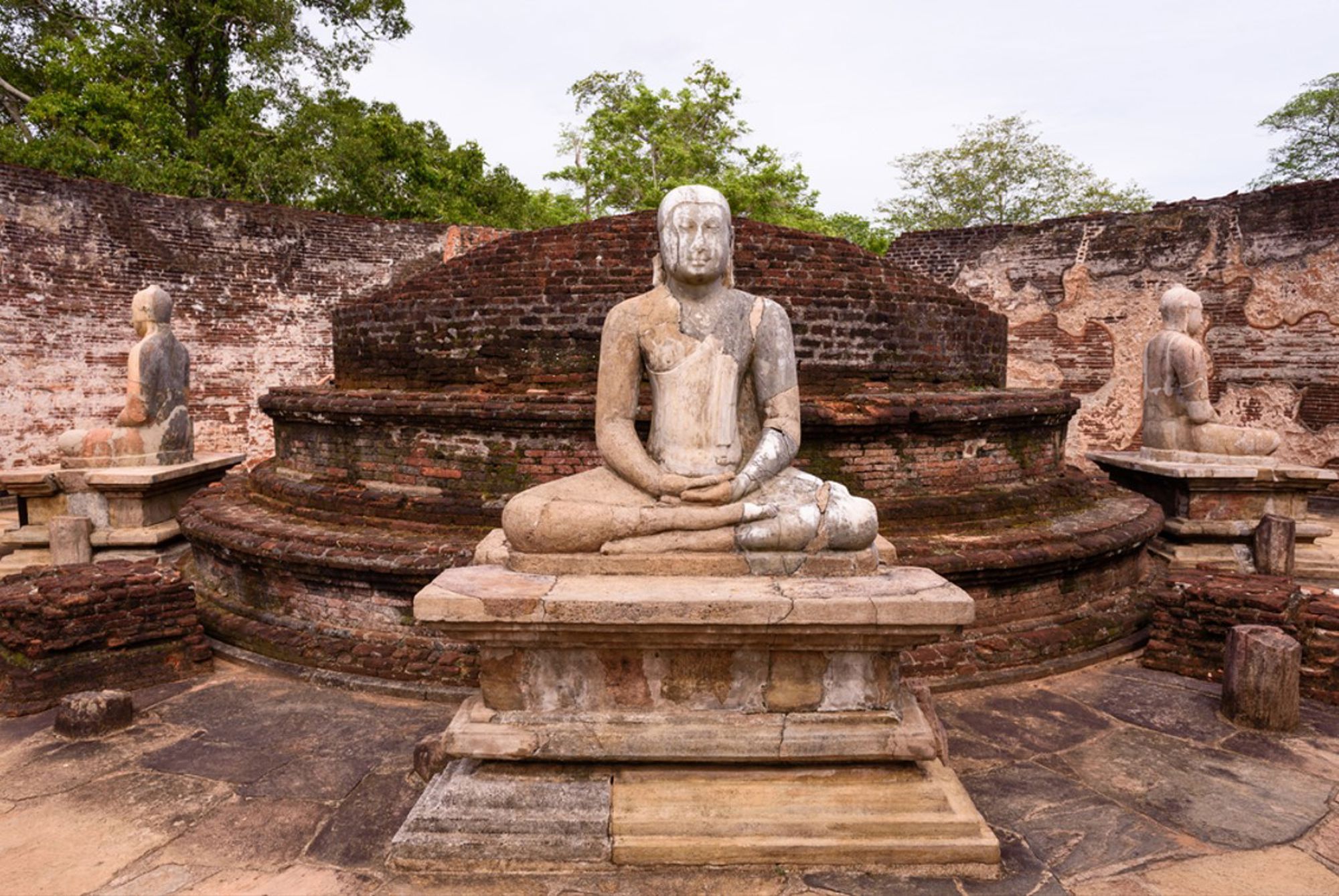 Zittend Boeddhabeeld in meditatieve houding bij een oude bakstenen tempelruïne in Sri Lanka.