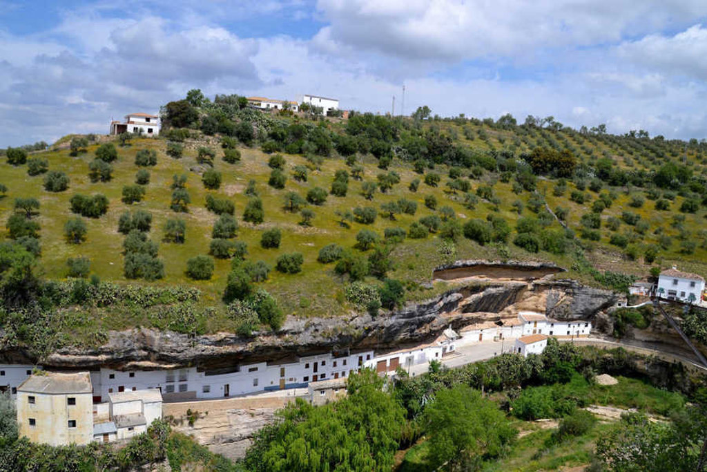 Wit dorp tegen een rotswand tussen olijfgaarden in Andalusië, Spanje.