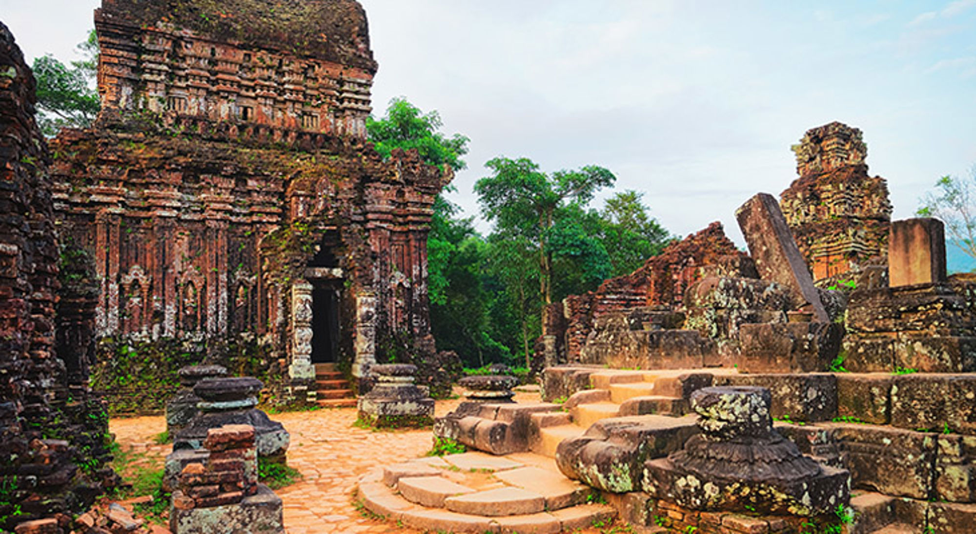 my-son-vietnam Oude tempelruïnes in My Son Sanctuary, Vietnam, met bakstenen torens en stenen paden tussen groen.