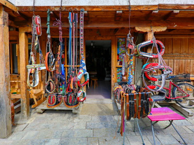 Traditionele paardenharnassen en leren riemen te koop bij een houten marktstalletje in Albanië, Kosovo en Noord-Macedonië.