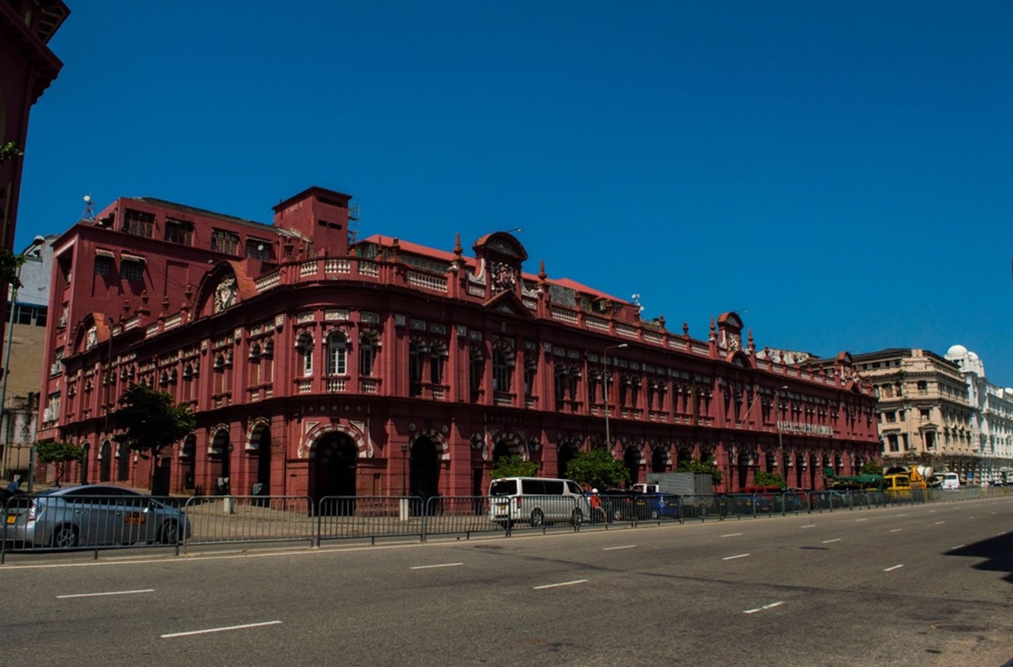 Rood Victoriaans gebouw in Colombo, Sri Lanka, met bogen en ornamenten langs een brede straat.