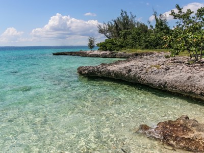 Rotsachtige kust met helder turquoise zeewater en groene begroeiing langs de Route Cuba.