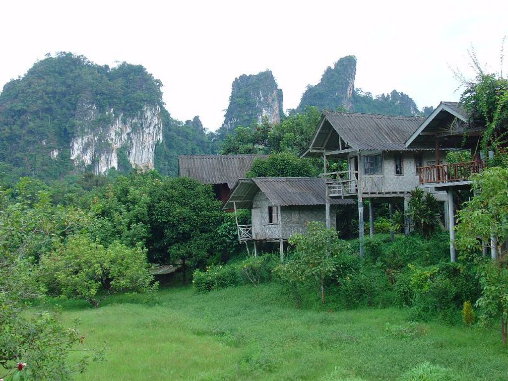 Bungalows in het groen met karstbergen op de achtergrond tijdens familiereis Thailand Noord en Zuid.