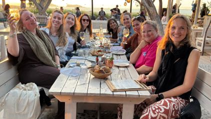 Twee reizigers proosten met bier op een terras met uitzicht op de Albanese kust.