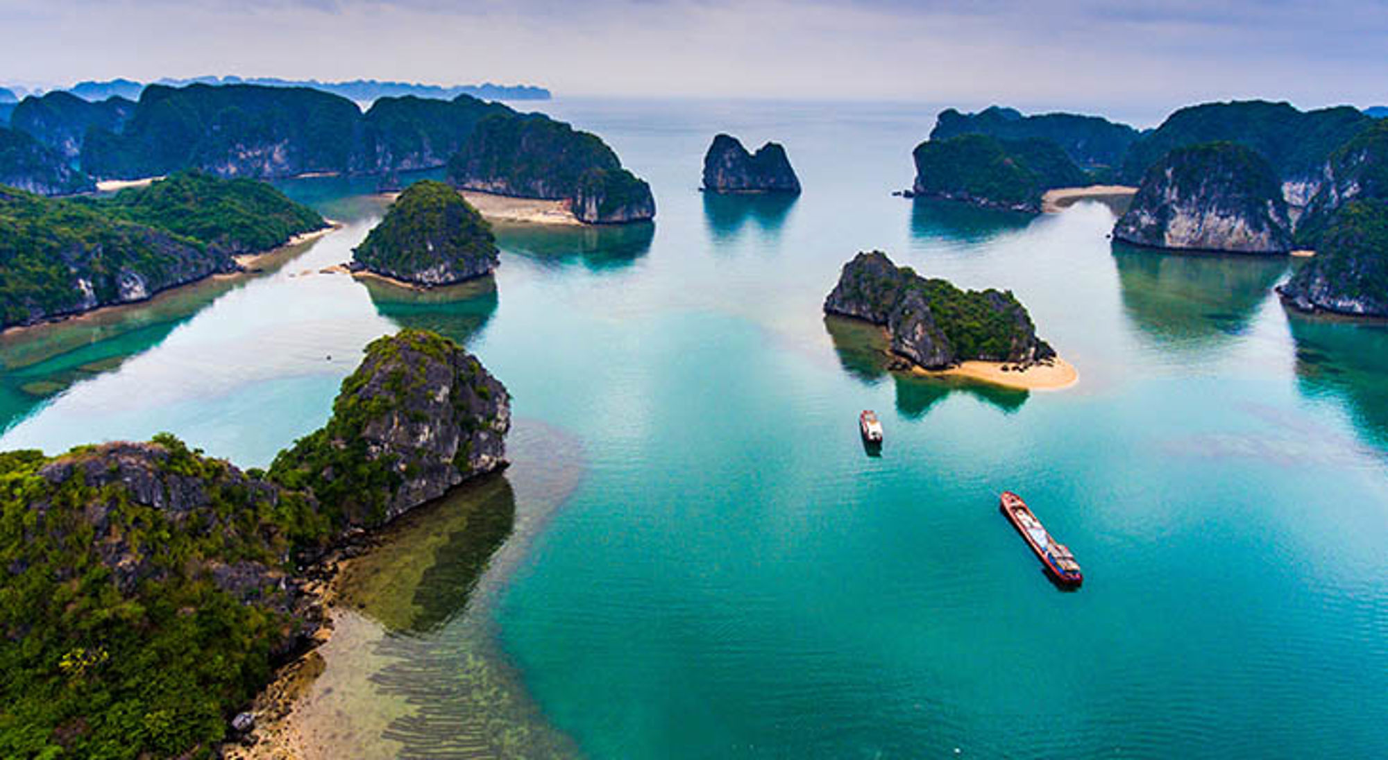 Cat Ba island Karst-eilanden en turquoise water in Halong Bay, Vietnam, met boten tussen de rotsformaties.