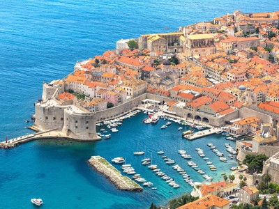 Uitzicht op de oude stad Dubrovnik met stadsmuren en haven vol boten aan de Adriatische Zee.
