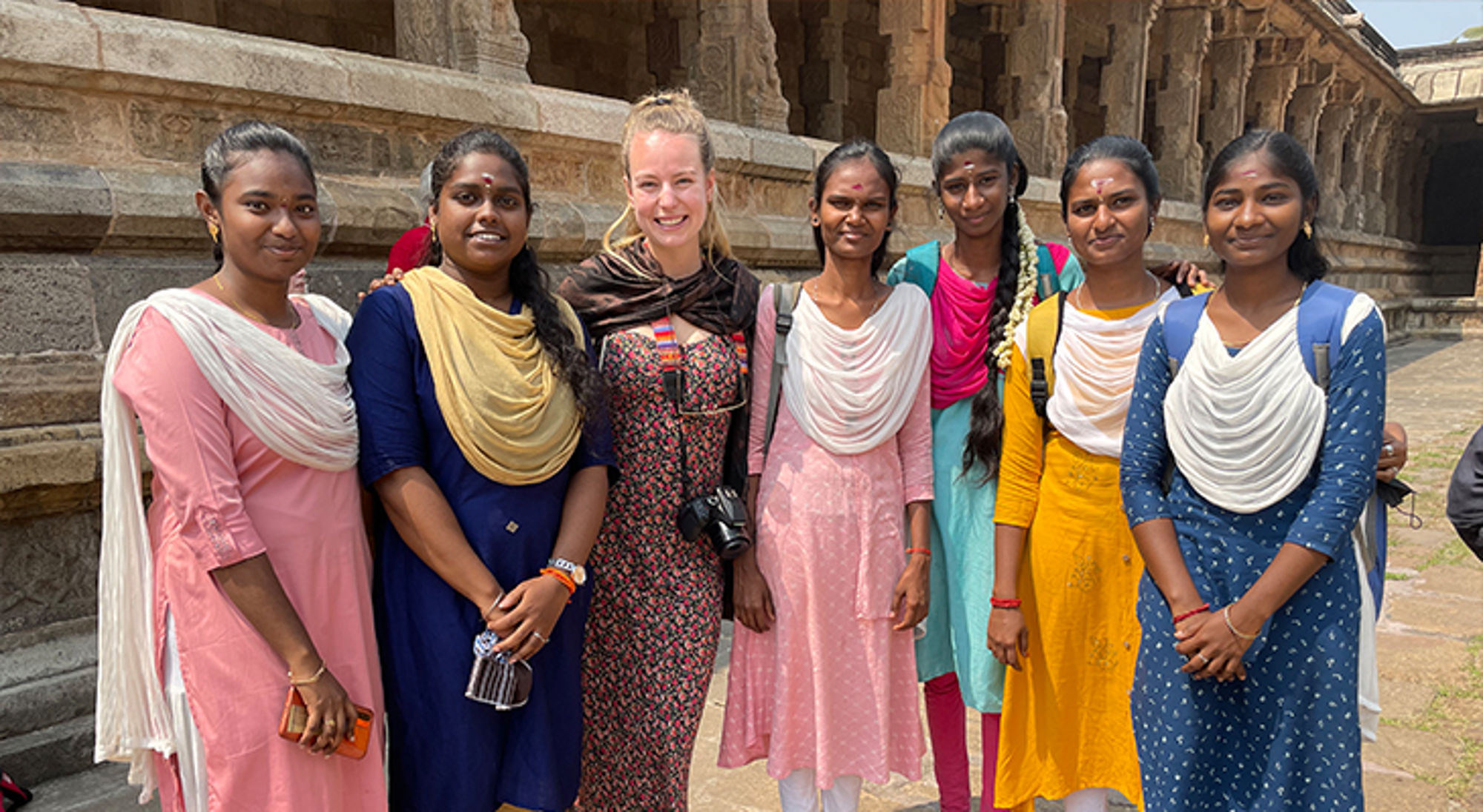 Doris Groepsfoto van reiziger met lokale studenten bij een tempelcomplex in India.