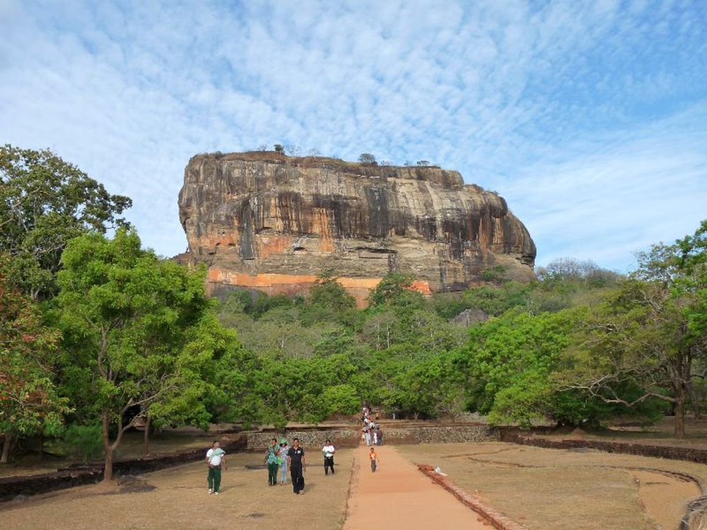 Sigiriya Leeuwenrots, iconische rotsvesting in Sri Lanka, omringd door groen en wandelpad met bezoekers.