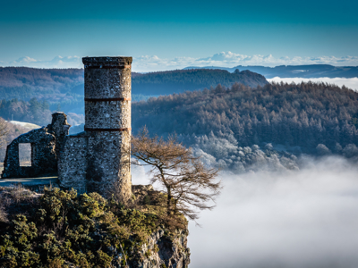 Ruïne van een stenen toren op een klif met uitzicht over mistige hooglanden in Schotland.