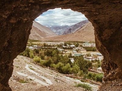 Uitzicht vanuit een grot op een dorp in de Ladakh-vallei, omringd door ruige bergen.