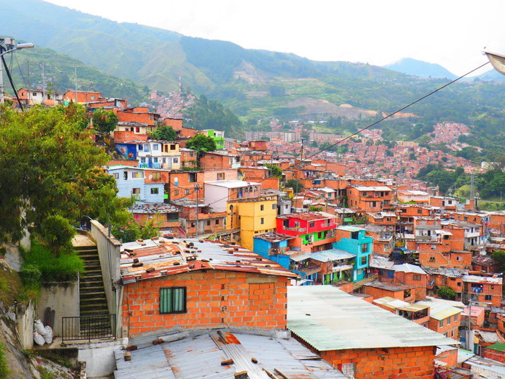 Kleurrijke huizen op een heuvel in Medellín, Colombia, met bergen op de achtergrond.