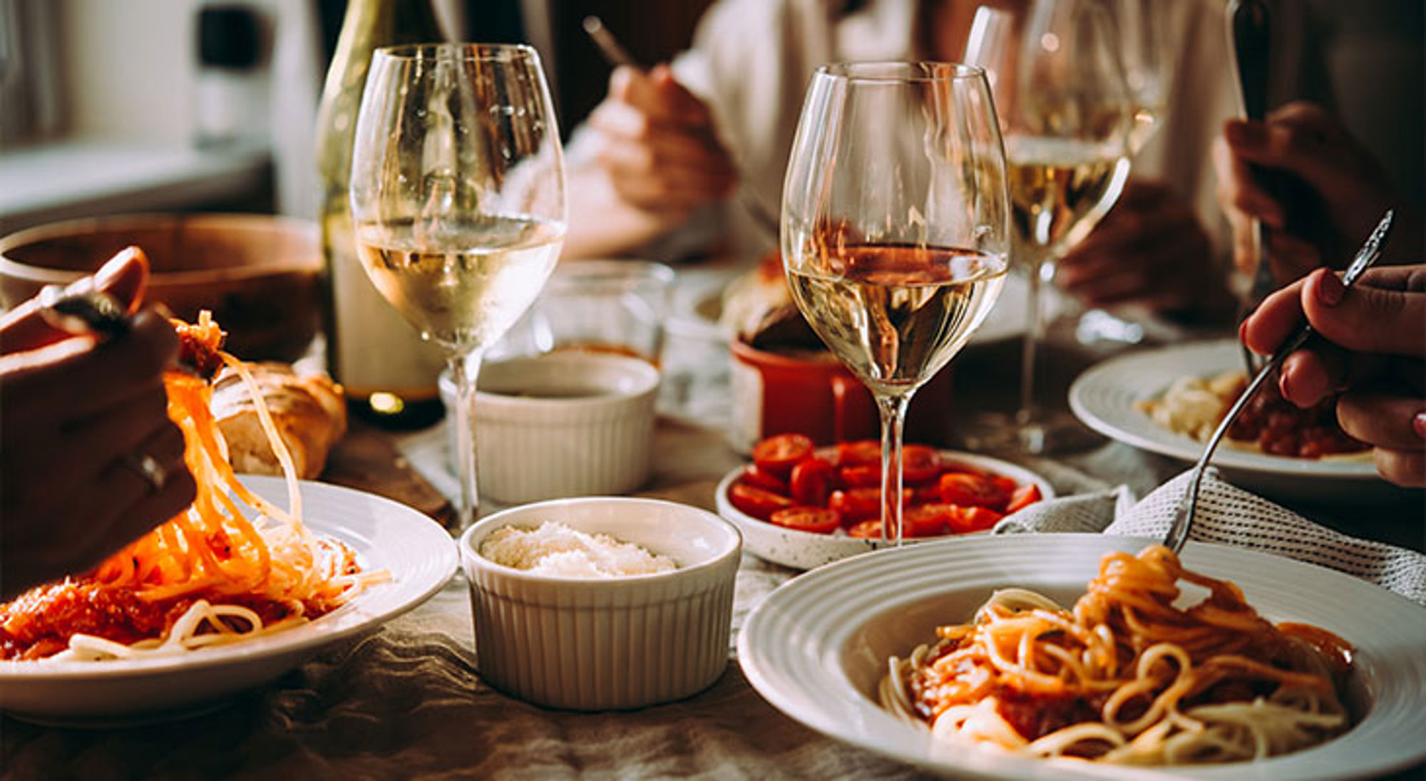 Italiaans diner Gezellig diner met borden pasta en glazen witte wijn op tafel.