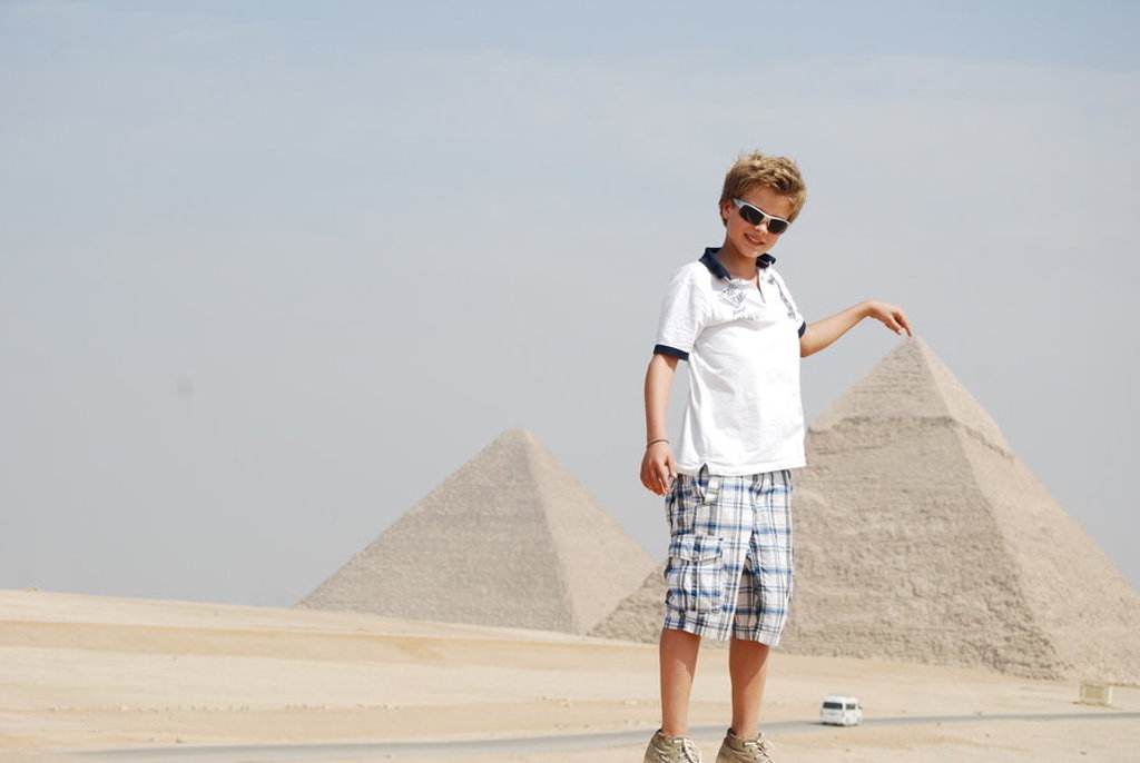 Kind poseert bij de piramides van Gizeh tijdens een familiereis in Egypte.