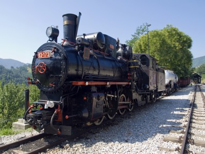 Stoomtrein op de Šargan Eight spoorlijn in de Balkan, met bergen op de achtergrond.