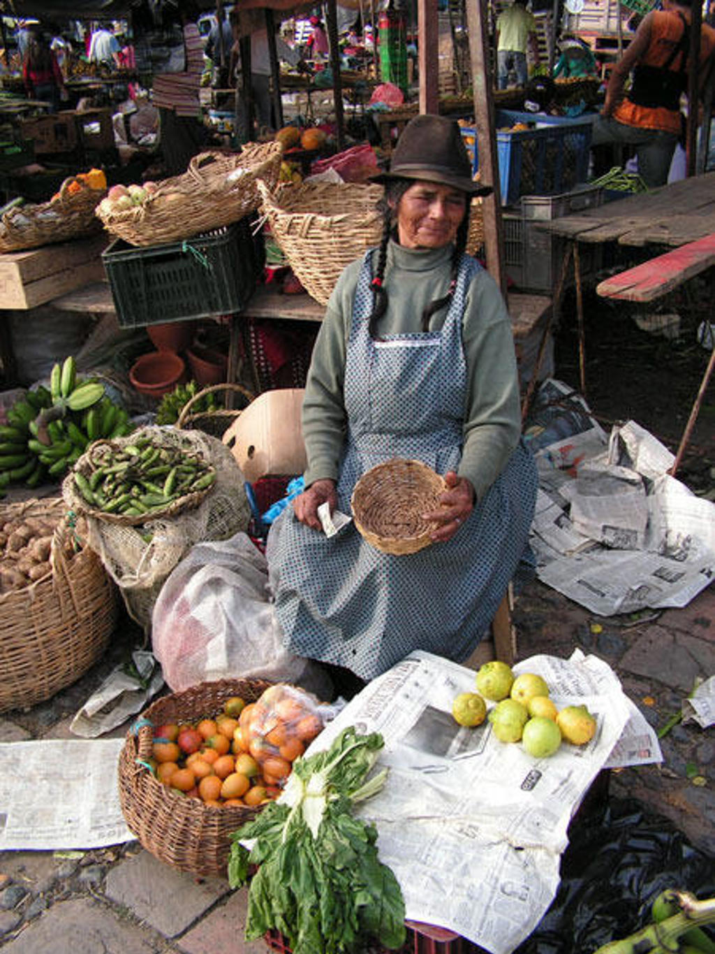 Marktvrouw op een lokale markt in Colombia met manden vol groente en fruit.
