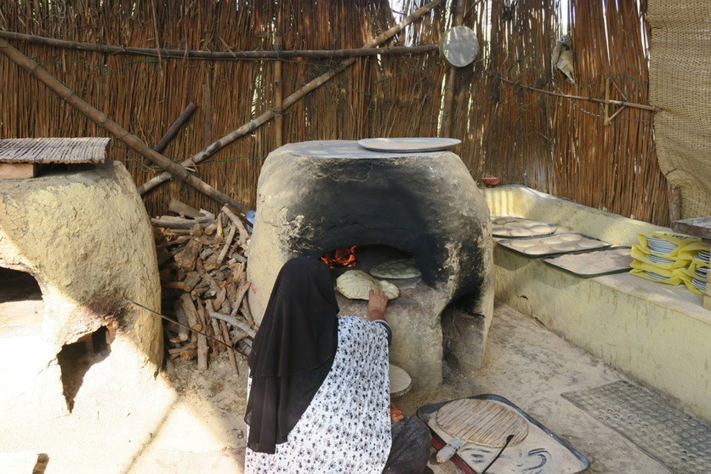 Vrouw bakt brood in een traditionele kleioven tijdens een groepsrondreis door Egypte.