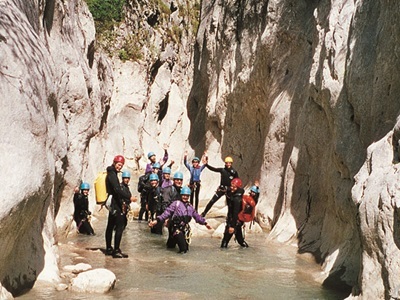 Canyoning in een smalle kloof in de Mercantour & Vésubie, met groep in wetsuits en helmen in het water.