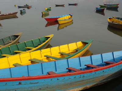 Gekleurde roeiboten op het rustige Phewa-meer in Pokhara, tijdens de Route Nepal Familiereis 15 dagen.