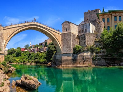 Stari Most-brug in Mostar over de Neretva, met historische gebouwen langs de oever.