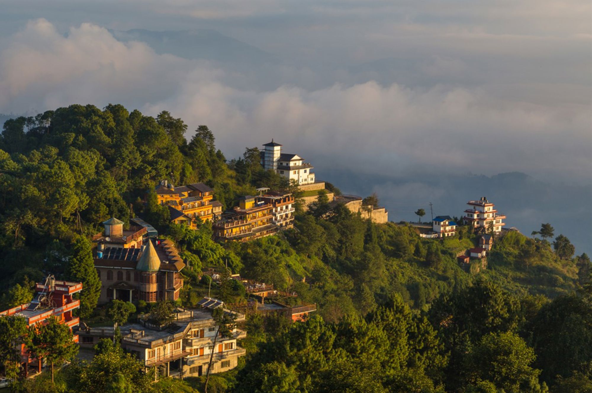 Uitzicht op Nagarkot in Nepal met heuveldorp en hotels boven de wolken bij zonsopkomst.