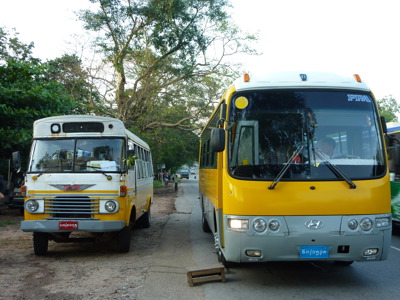Oude en moderne bus naast elkaar langs de weg in Myanmar tijdens de 25-daagse Route Birma.