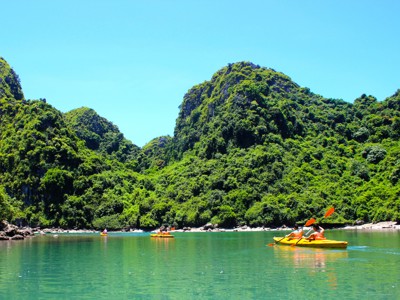 Kajakkers op groenblauw water tussen kalksteenbergen in Halong Bay, Vietnam.