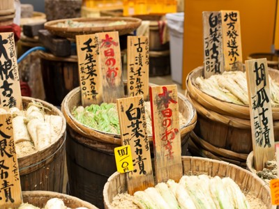 Vaten met ingelegde groenten en Japanse prijsbordjes op een lokale markt in Japan.