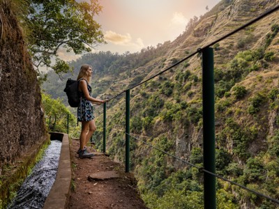 Wandelaar langs een levada-pad met uitzicht op groene berghellingen op Madeira.