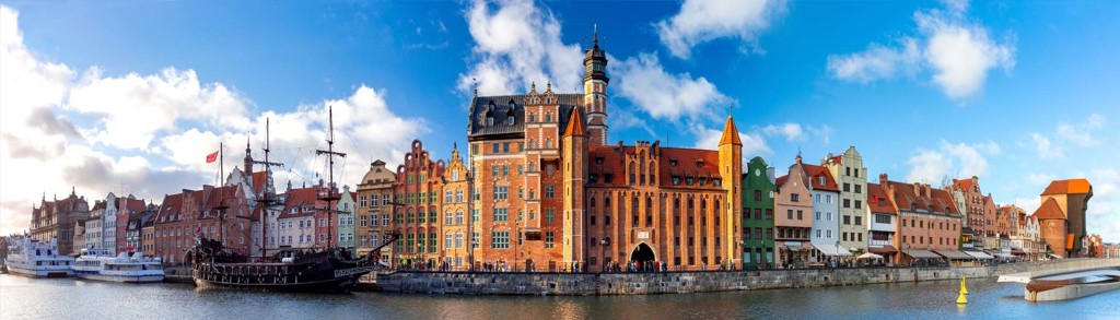 Panorama van de historische haven van Gdańsk met kleurrijke gevels en de middeleeuwse kraan aan de rivier de Motława.