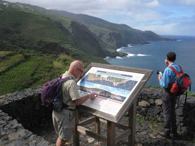 Wandelaars bij informatiebord met uitzicht op de ruige kustlijn van Tenerife tijdens de 10-daagse wandelvakantie.