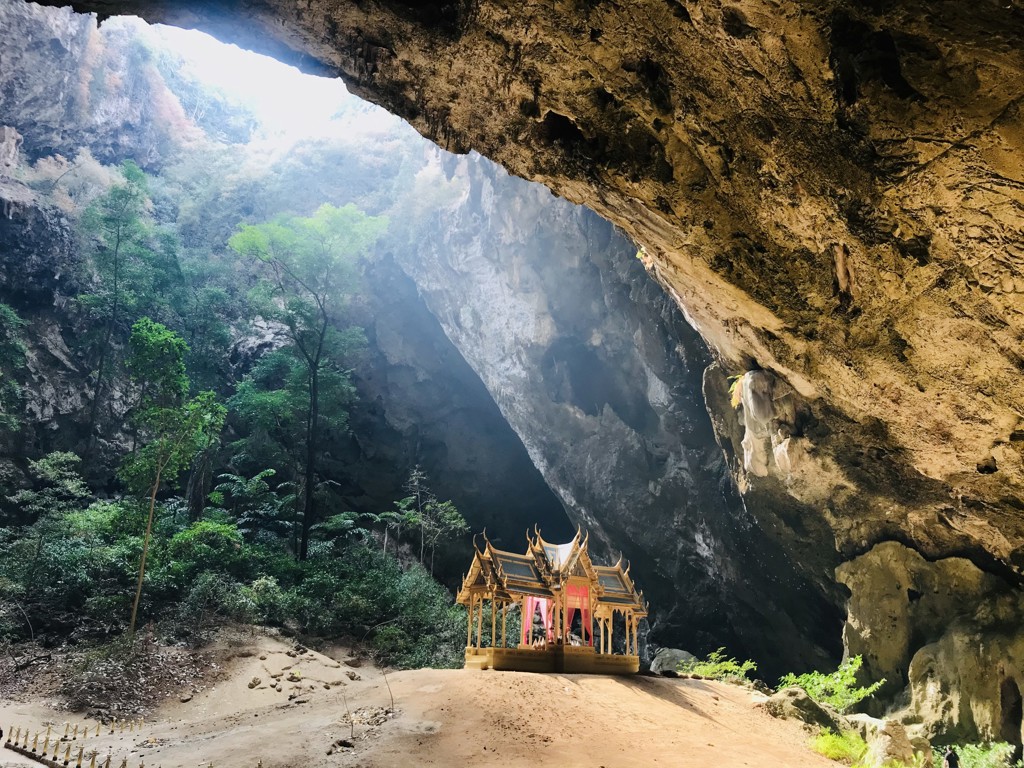 Gouden tempelpaviljoen in een grot met zonnestralen en groen, tijdens groepsrondreis Thailand avontuur.