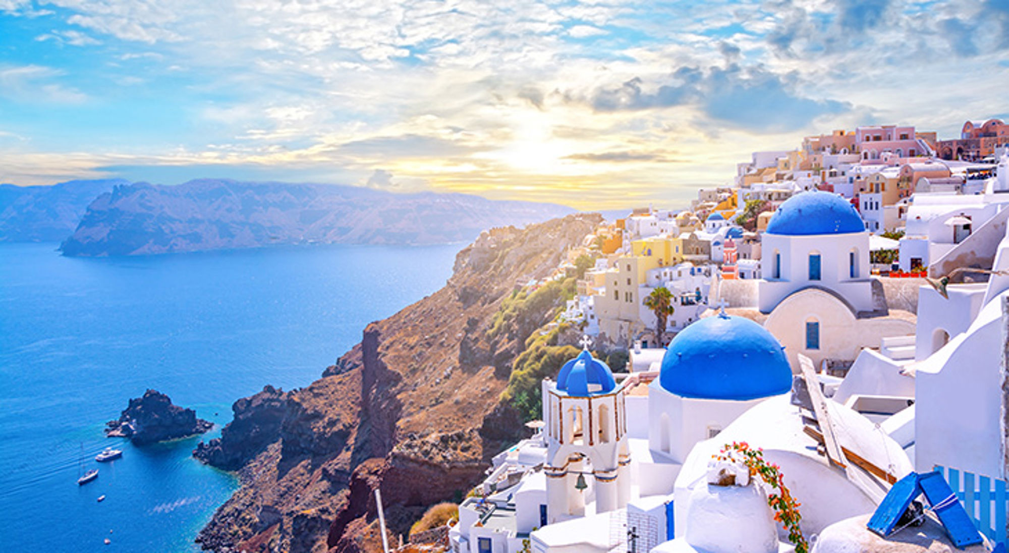 griekenland-santorini Zonsondergang boven Oia op Santorini met witgekalkte huizen en blauwe koepelkerken aan de kliffen.