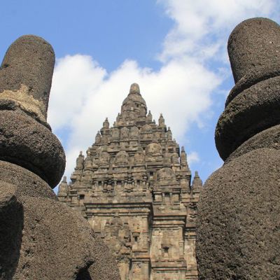 Prambanan-tempelcomplex op Java, gezien tussen twee stenen beelden, tijdens groepsrondreis Java, Bali en Lombok.