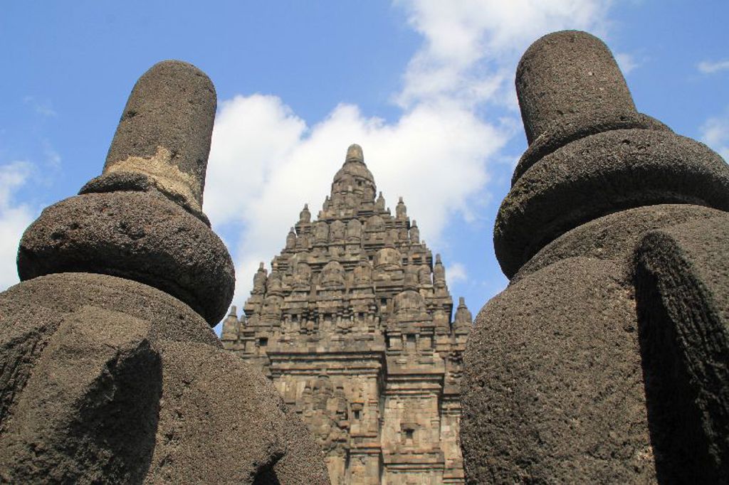 Prambanan-tempelcomplex op Java, gezien tussen twee stenen beelden, tijdens groepsrondreis Java, Bali en Lombok.